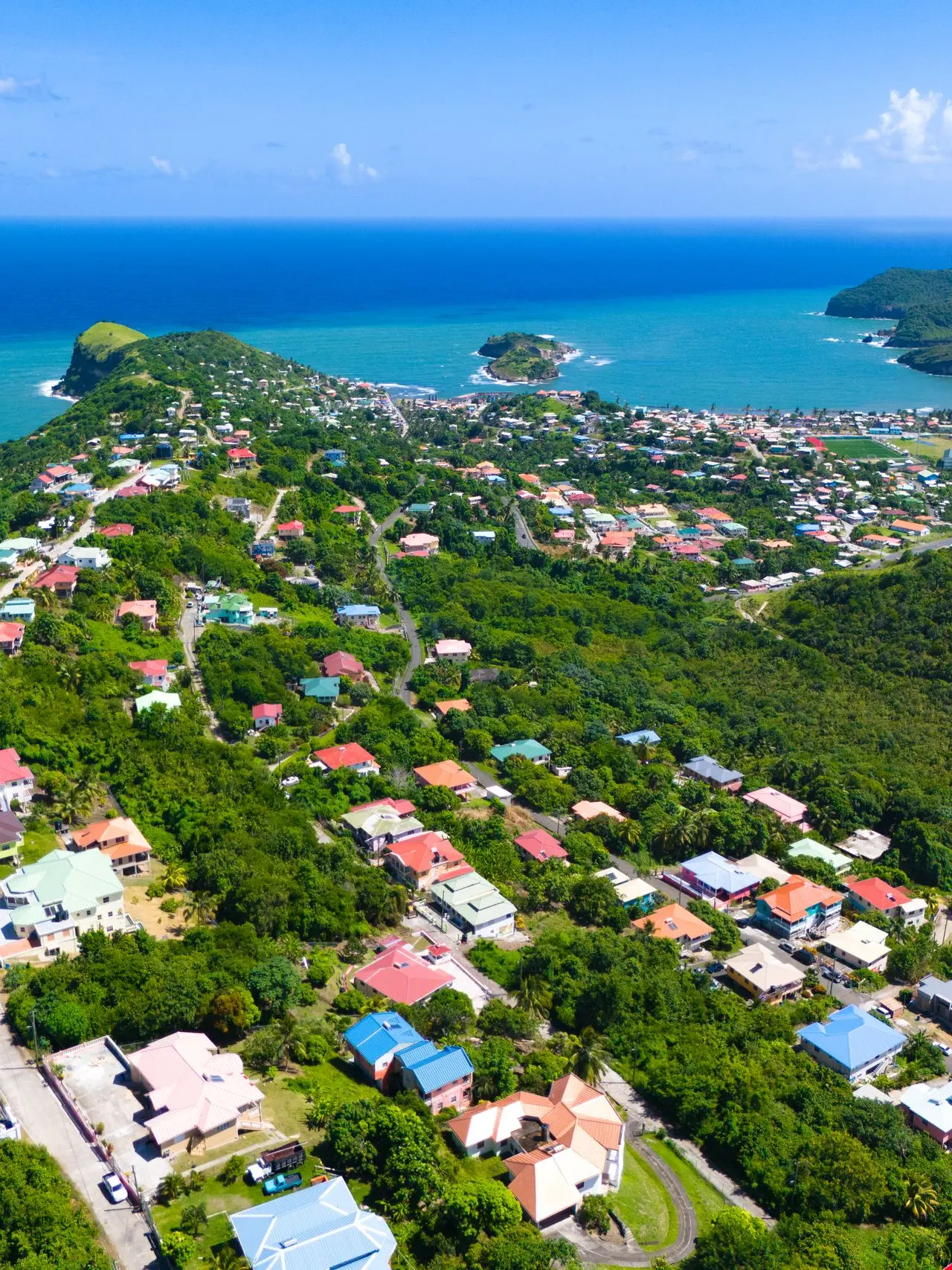 A coastal community framed by sea and green hills.