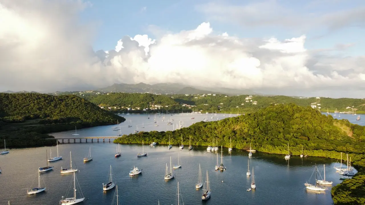 An aerial view of sailboats across a sheltered natural harbour.