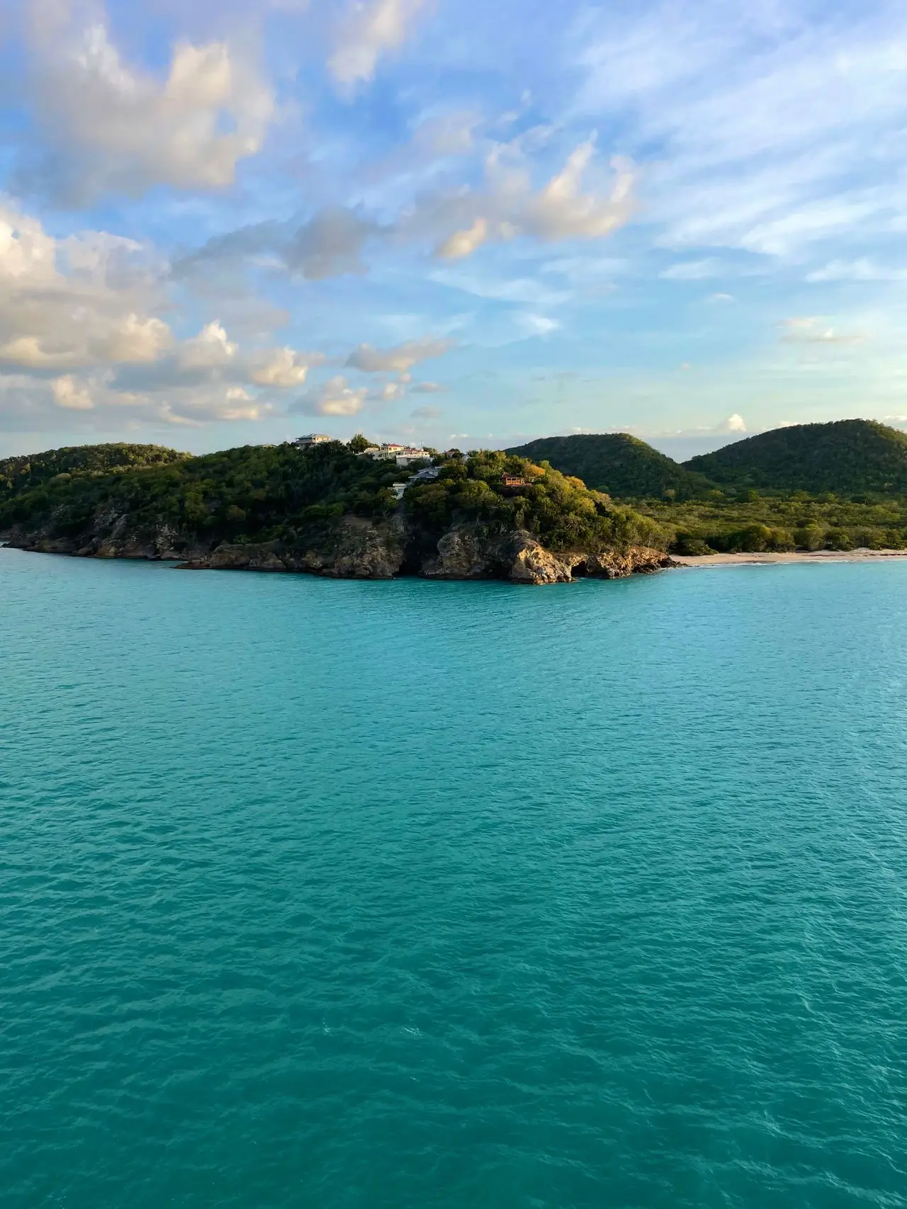 Turquoise water and a green island coastline viewed from above.